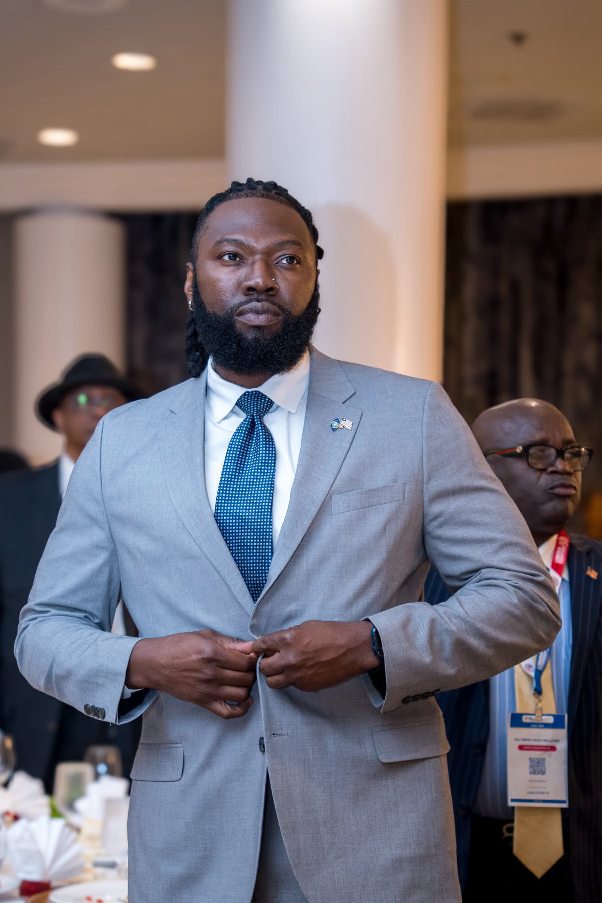 Lawrence Totimeh Jr. in a gray suit with a Liberian flag lapel pin